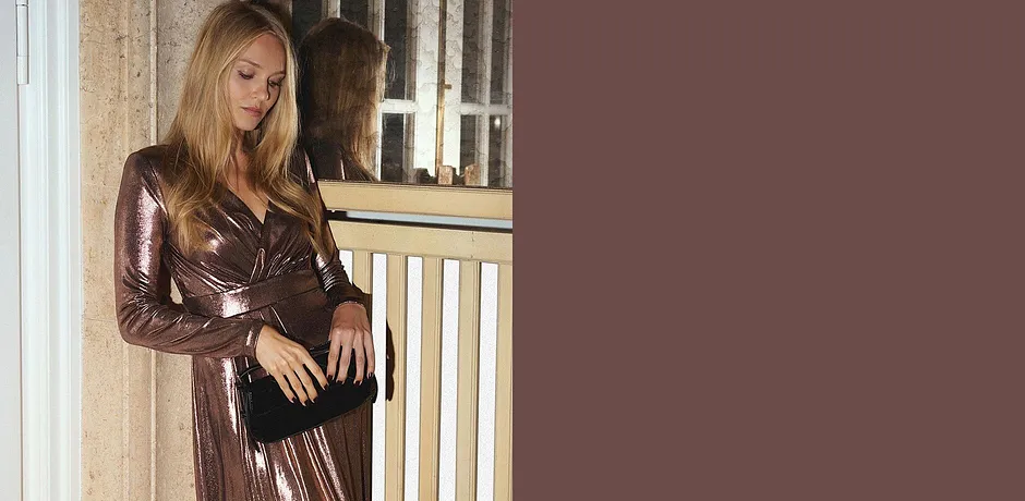 Glitrende kjole med V-hals kombinert med sort veske.