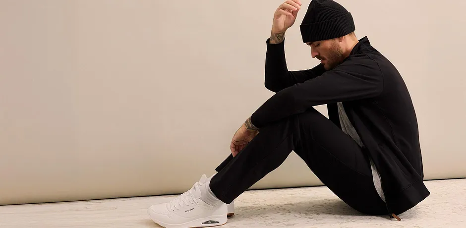 Sort joggedress kombinert med lue og hvite sneakers.