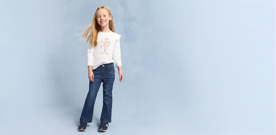 Ledig look med hvit, langermet topp og jeans med utsvingte ben.