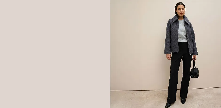 Grå jakke, grå genser og sort bukse.