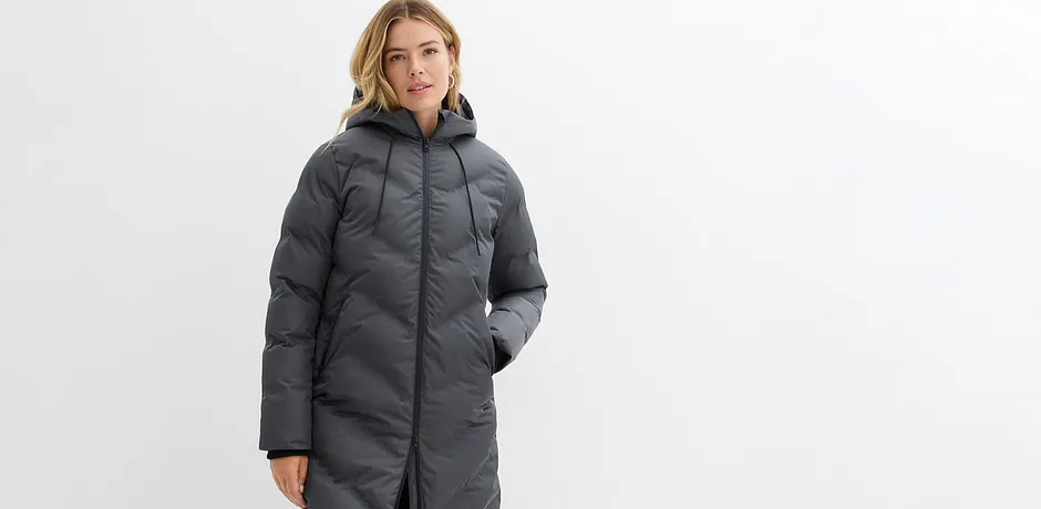 Lang, grå vinterkåpe med hette og glidelås.