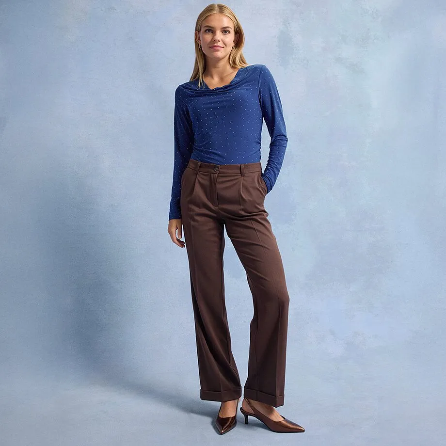 Blå langermet topp med prikker, brun bukse med vide ben og spisse, brune sko.