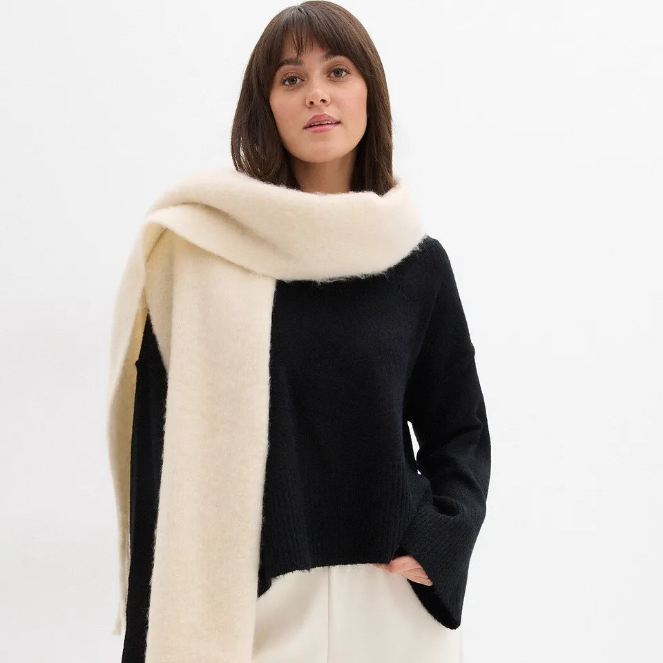 Sort genser kombinert med kremfarget skjerf.