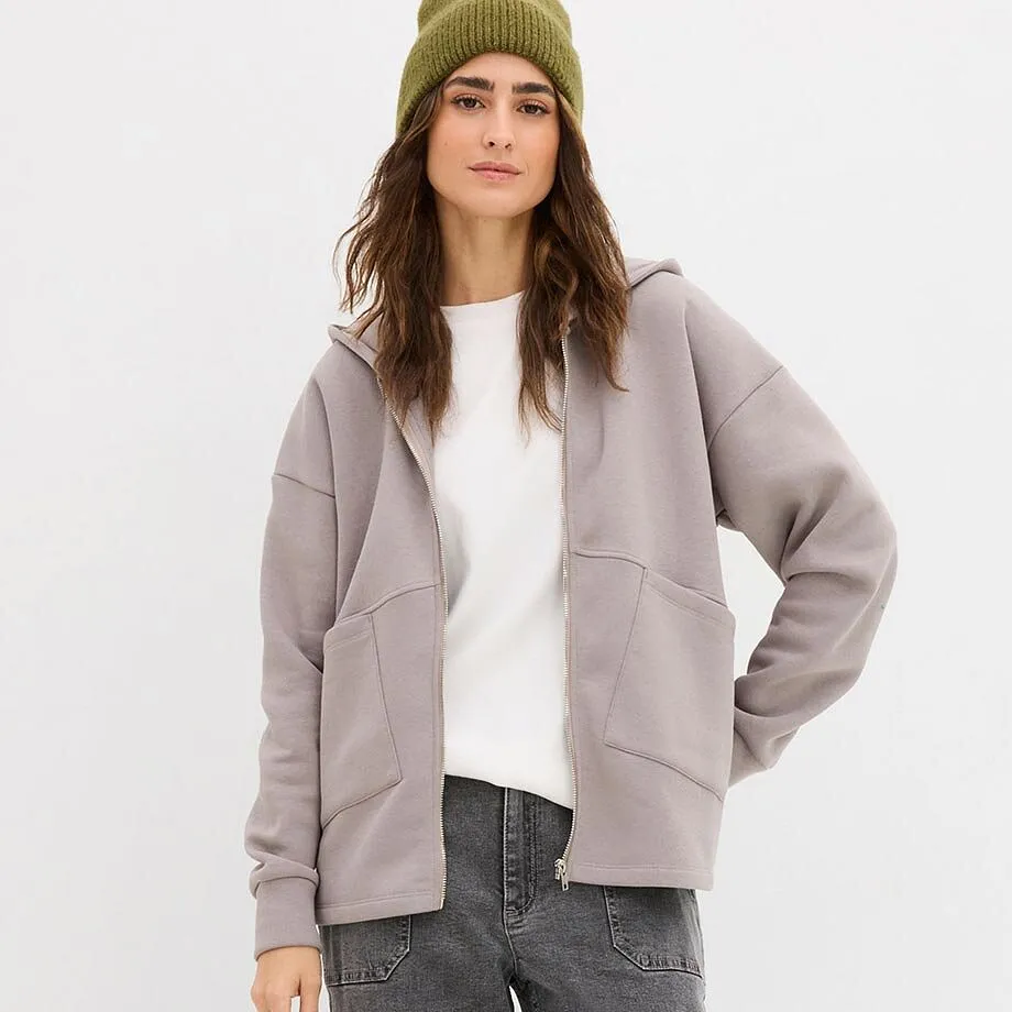 Hvit topp og grå sweatjakke over grå jeans.