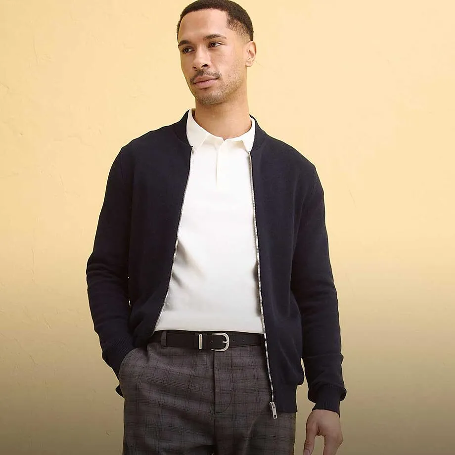 M&oslash;rk cardigan over hvit poloskjorte kombinert med gr&aring; bukse.