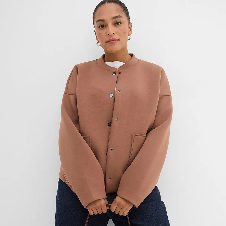Terrakottafarget jakke med trykknapper og rund hals.