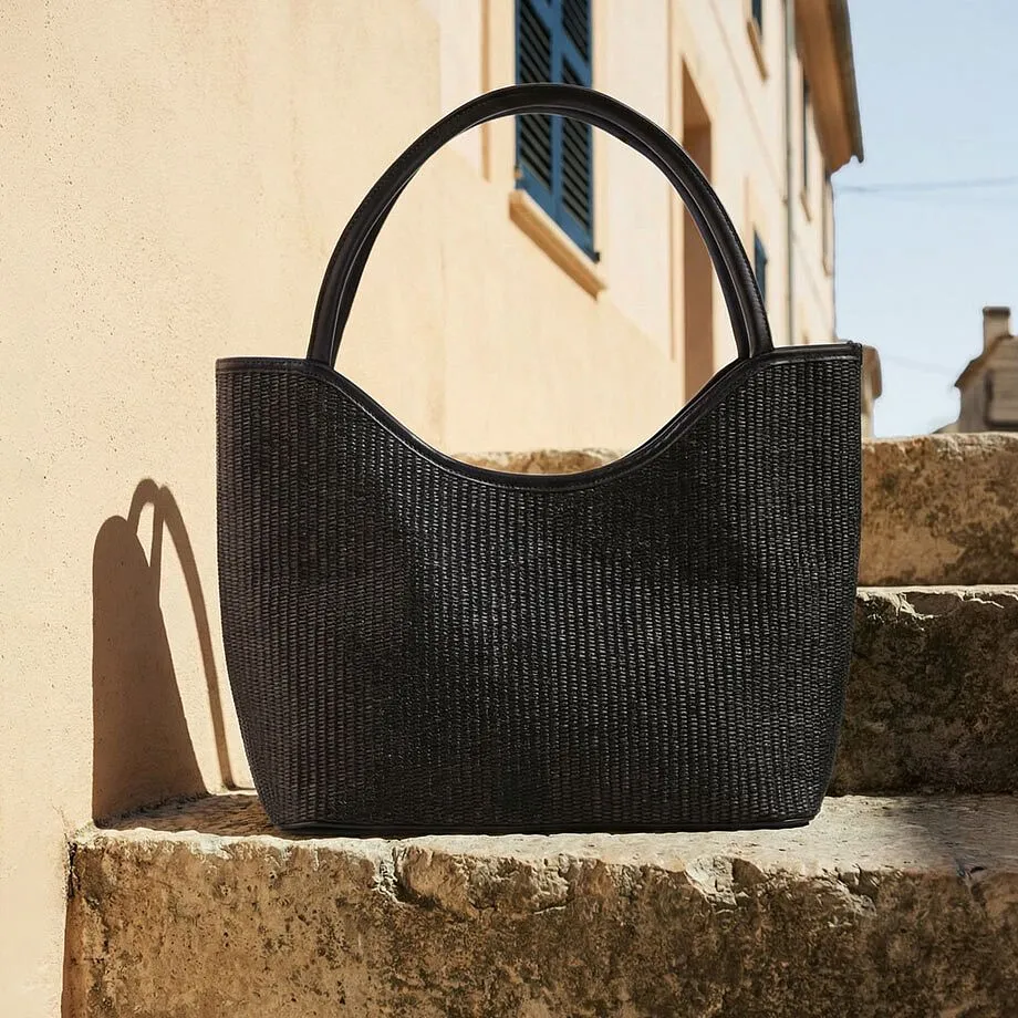 Sort veske i flettet materiale.