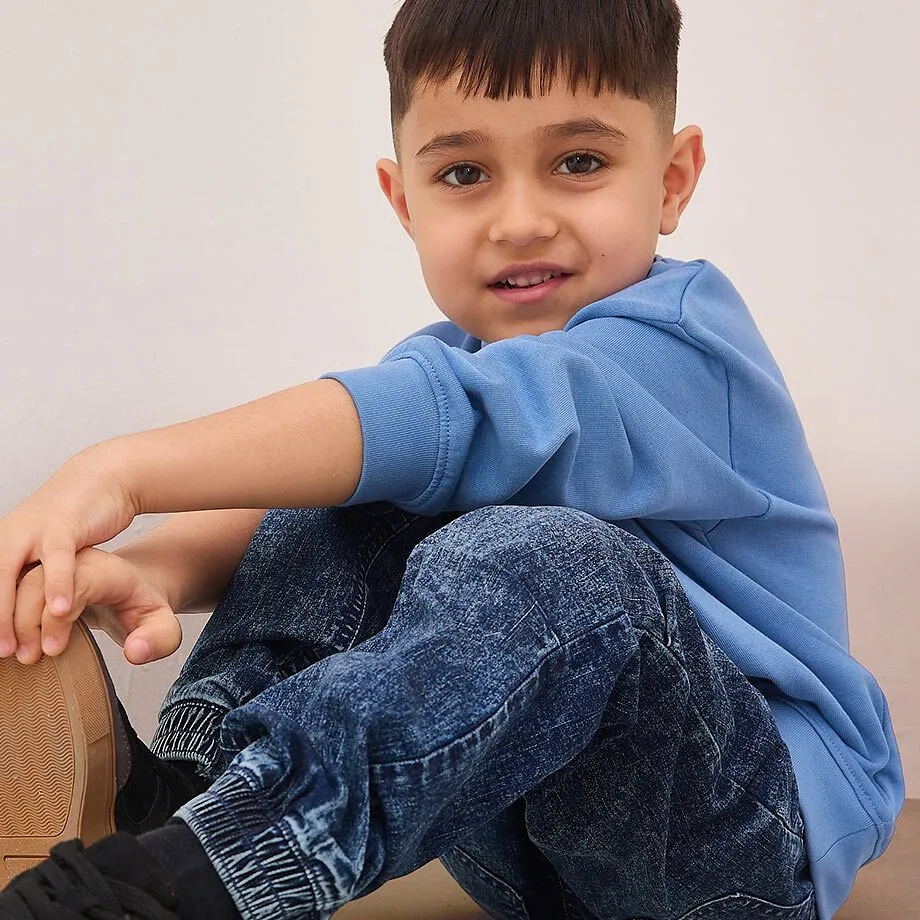 Bl&aring; genser og m&oslash;nstrede jeans for en avslappet, ung stil.