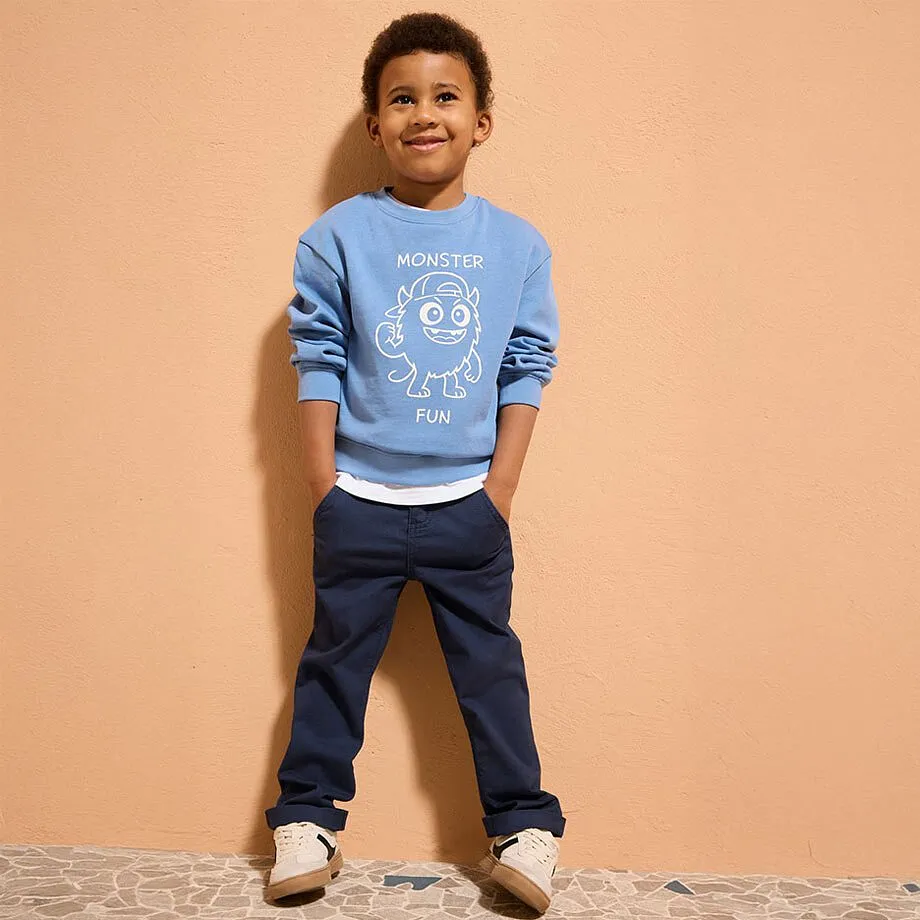 Lysebl&aring; genser med trykk, m&oslash;rke jeans og beige sko skaper et avslappet antrekk.