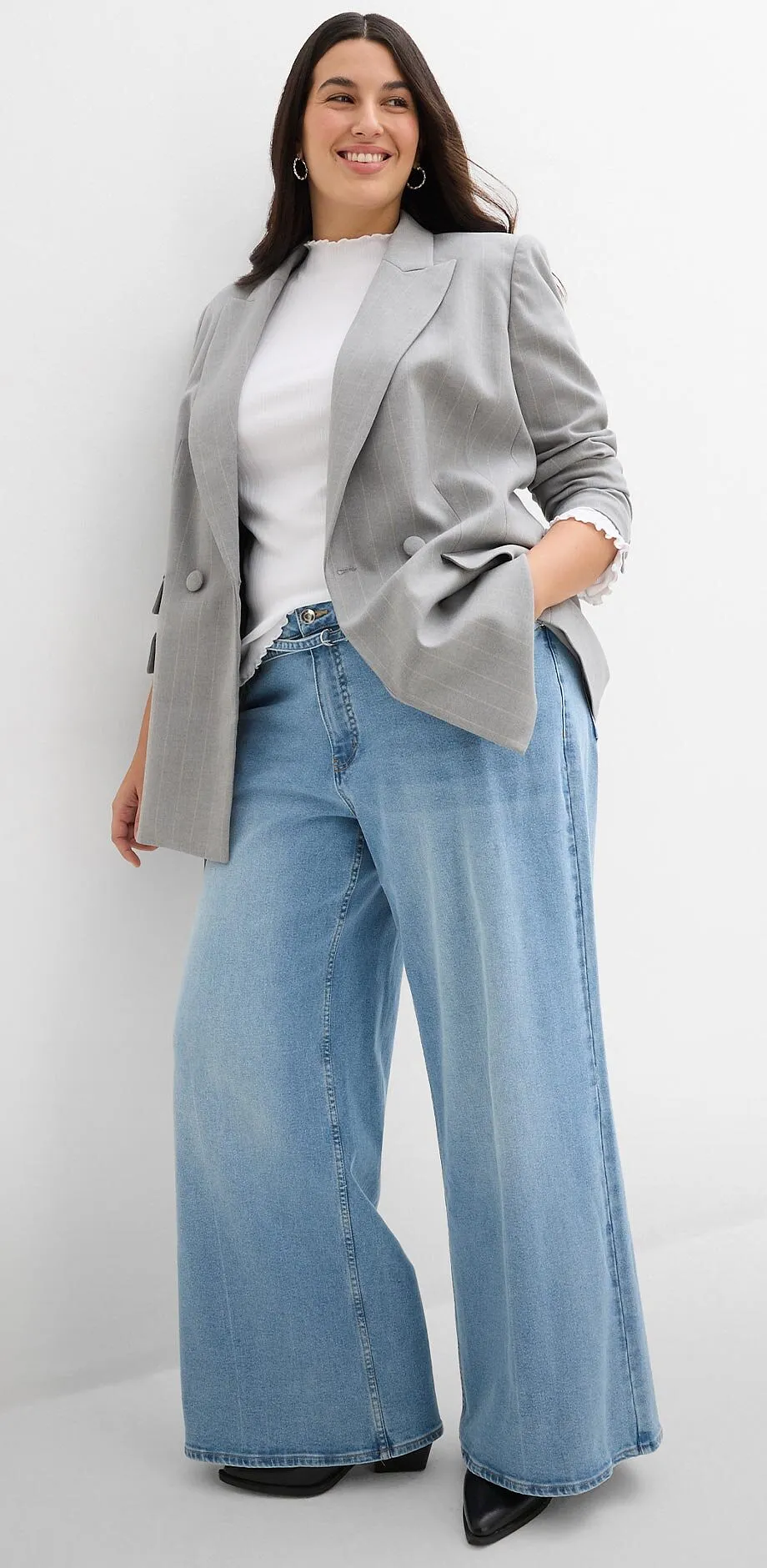 Elegant, gr&aring; blazer, hvit topp og vide jeans.
