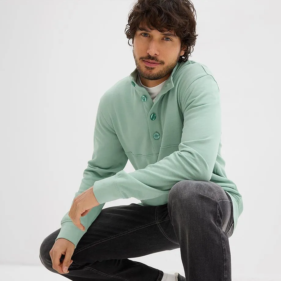 Mintgr&oslash;nn sweatshirt med knappestolpe, hvit shirt under og m&oslash;rke jeans.