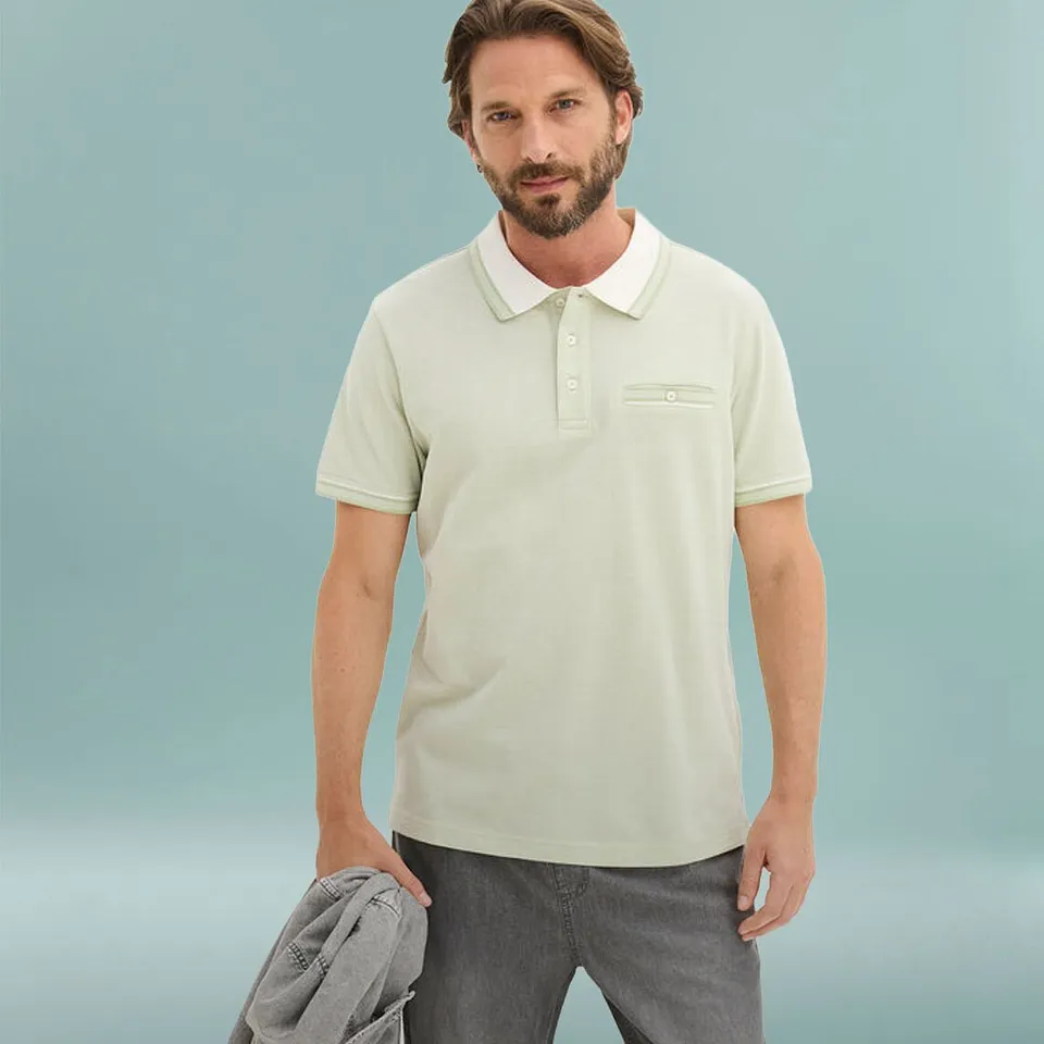 Mann i lysegr&oslash;nn poloskjorte med hvit krage og gr&aring; bukse.