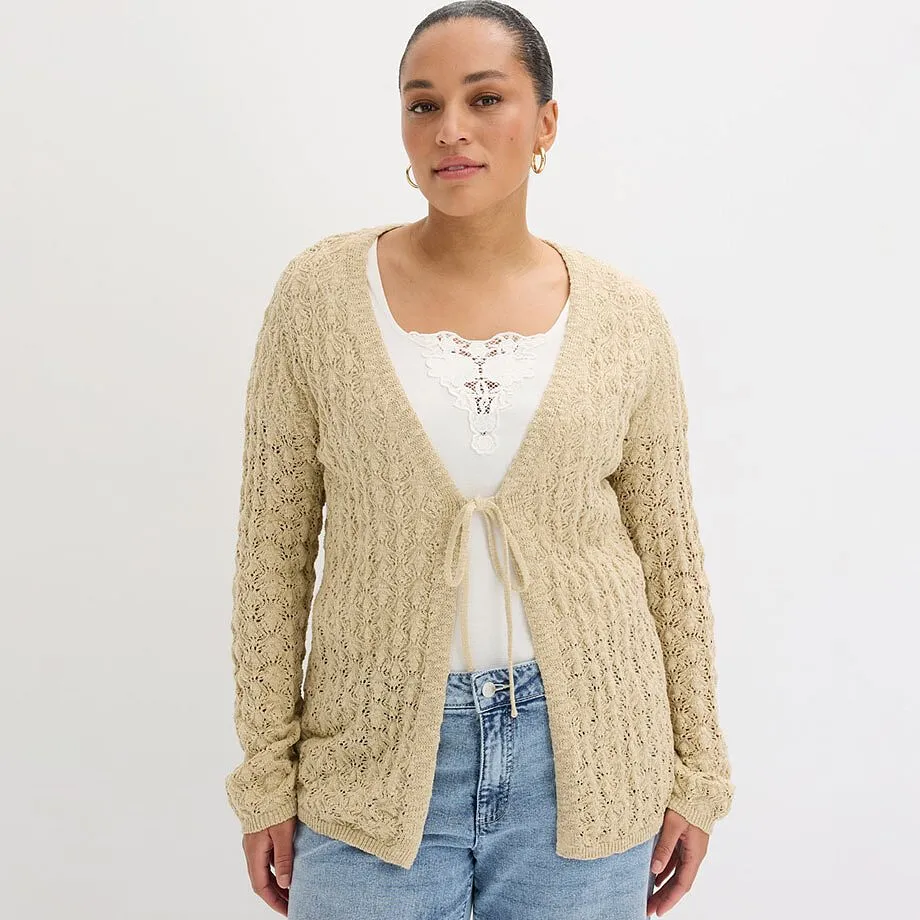 Beige cardigan over hvit topp kombinert med klassiske bluejeans.