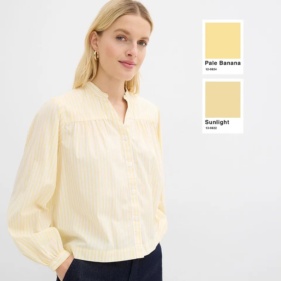 Lysegul bluse med fine striper og lange ermer.