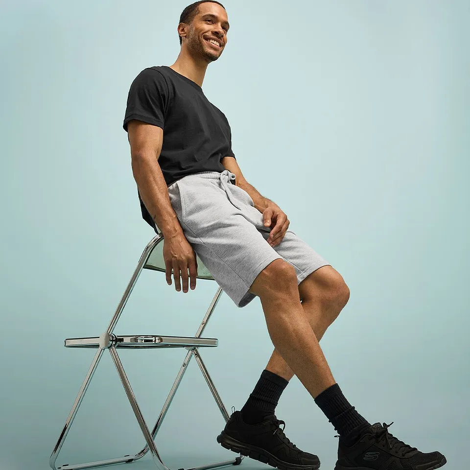 Avslappet look med sort T-skjorte, lys shorts og m&oslash;rke sneakers.