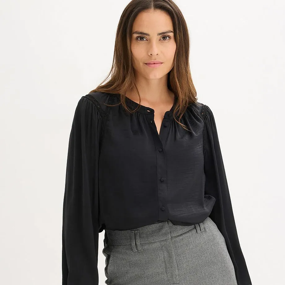 Elegant, sort bluse med V-hals kombinert med gr&aring; bukser.