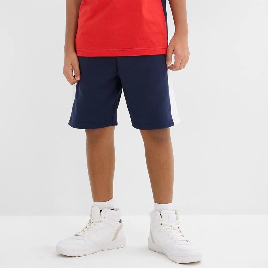 Et barn i r&oslash;d shirt, m&oslash;rkebl&aring; shorts.