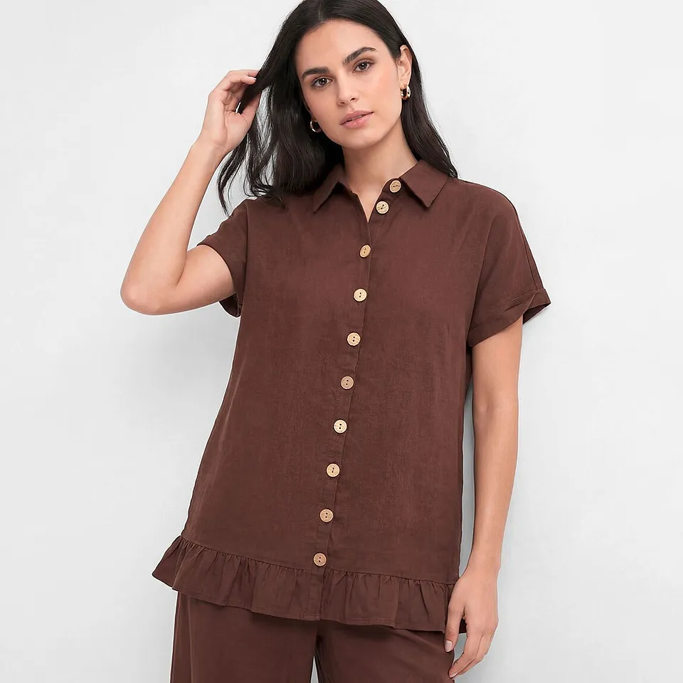 Brun bluse med korte ermer og lyse knapper.