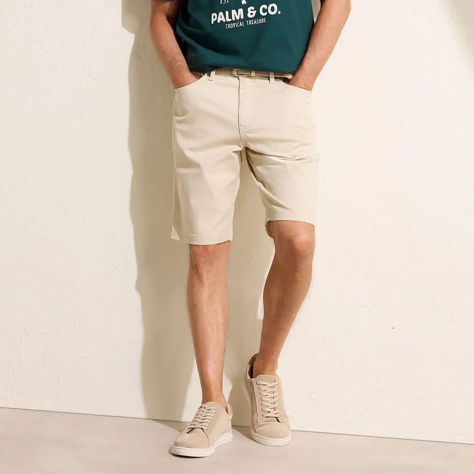 Gr&oslash;nn T-skjorte med trykk, beige chinosshorts og lyse sneakers.