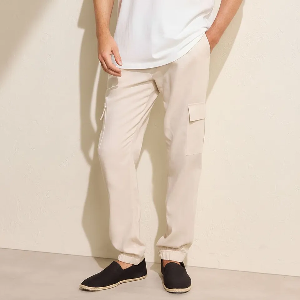 Avslappet look med hvit T-skjorte, beige cargobukse og m&oslash;rke slip on-sko.
