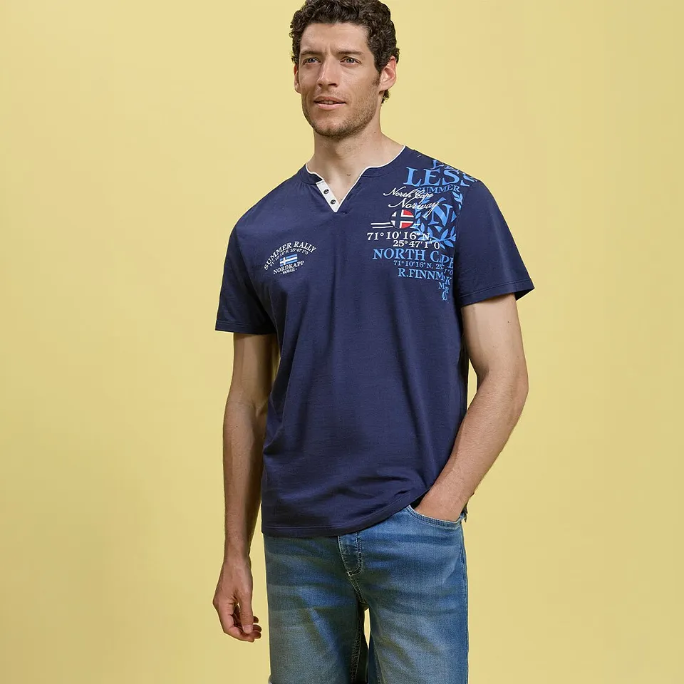 Person i avslappet, m&oslash;rkebl&aring; bestefartr&oslash;ye med i&oslash;ynefallende print og lyse jeans.