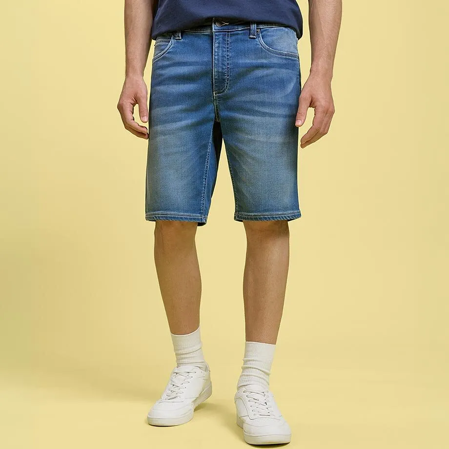 Avslappet denimshorts og bl&aring; T-skjorte kombinert med hvite sneakers og sokker.