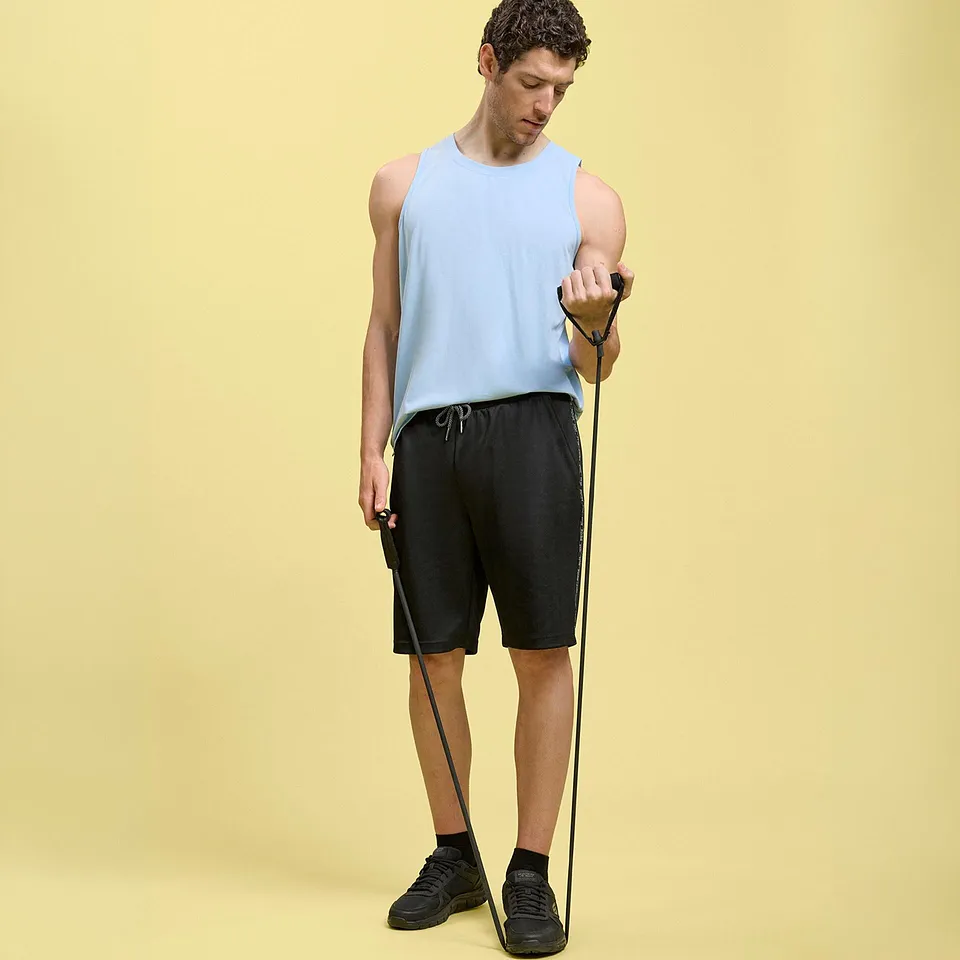 Person i lysebl&aring; singlet, sort shorts og m&oslash;rke joggesko.