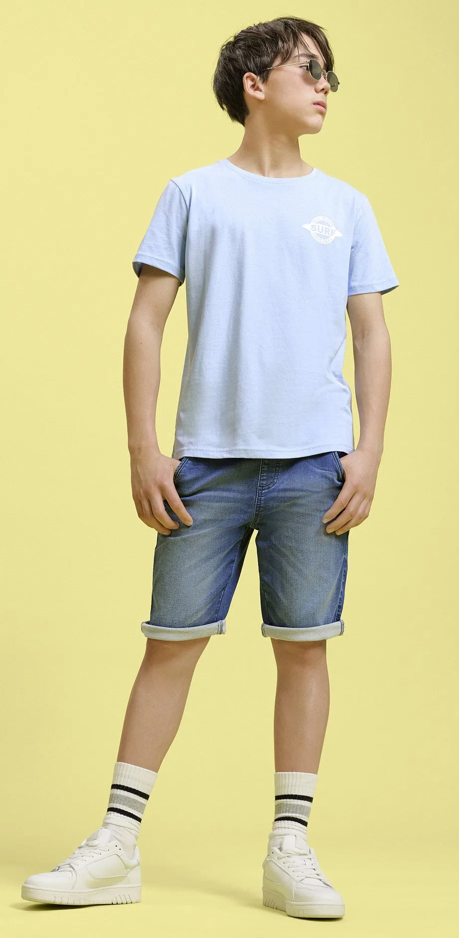 Lysebl&aring; T-skjorte og denimshorts.