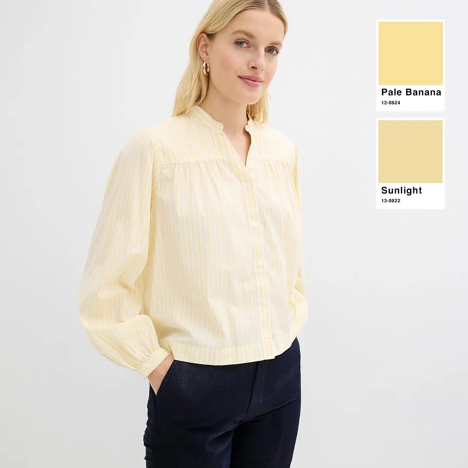 Lysegul bluse med fine striper og lange ermer.