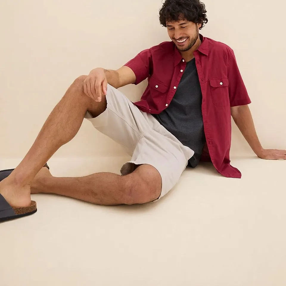 R&oslash;d, kortermet skjorte over m&oslash;rk T-skjorte kombinert med lys shorts og behagelige sandaler.