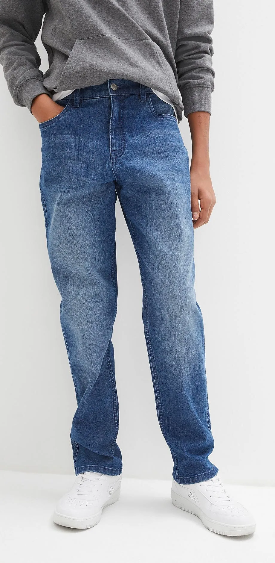 Gr&aring; hettegenser, bluejeans og hvite sneakers skaper et avslappet antrekk.