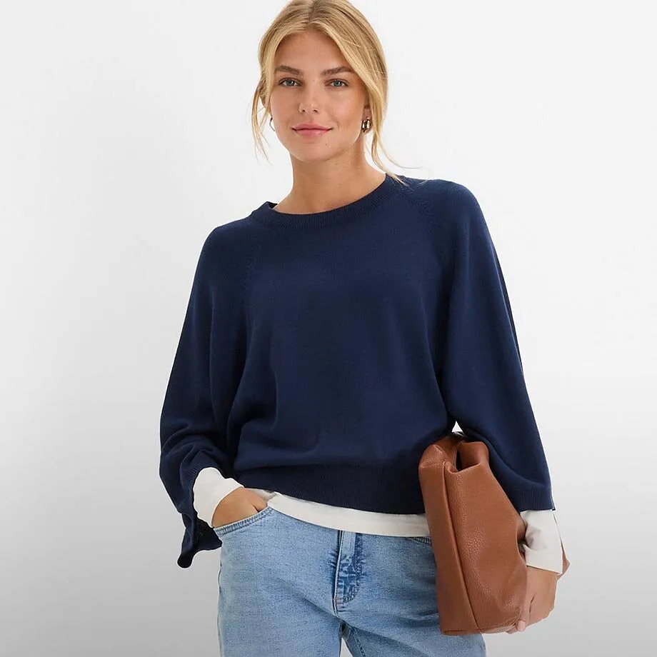 M&oslash;rkebl&aring; genser, lyse jeans og brun h&aring;ndveske.