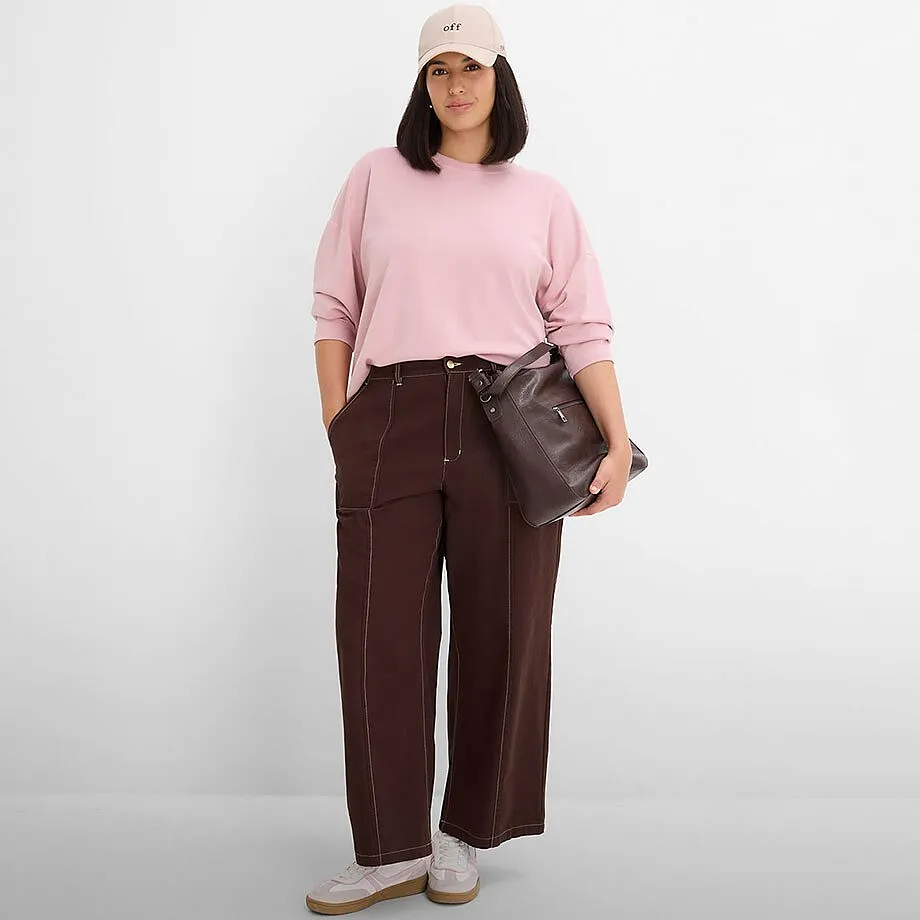 Rosa sweatshirt, brun bukse med vide ben, beige caps og m&oslash;rk veske.