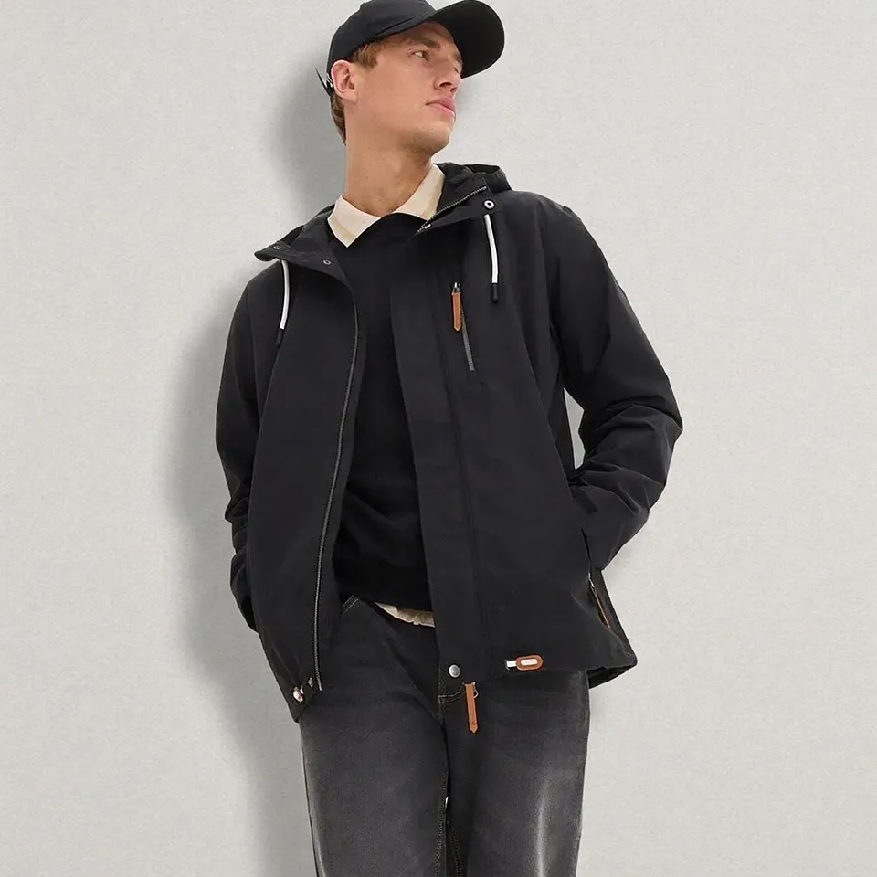 Sort jakke med hette, jeans, genser og caps.