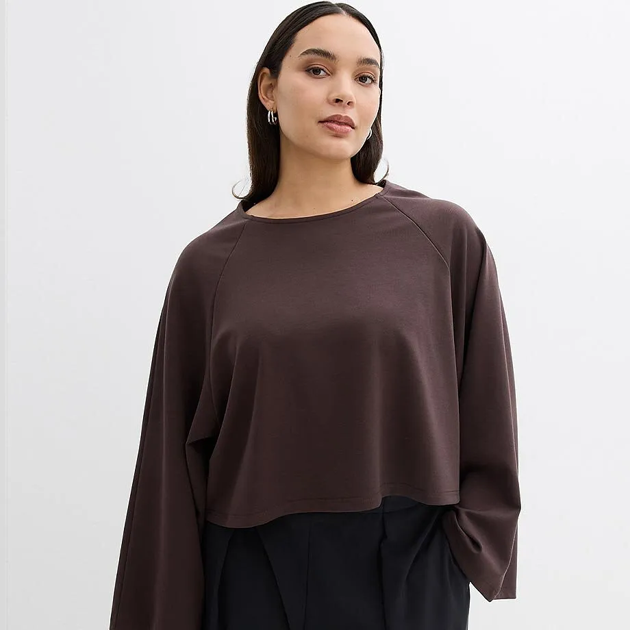 M&oslash;rkebrun, langermet topp med vide ermer og elegant, sort bukse.