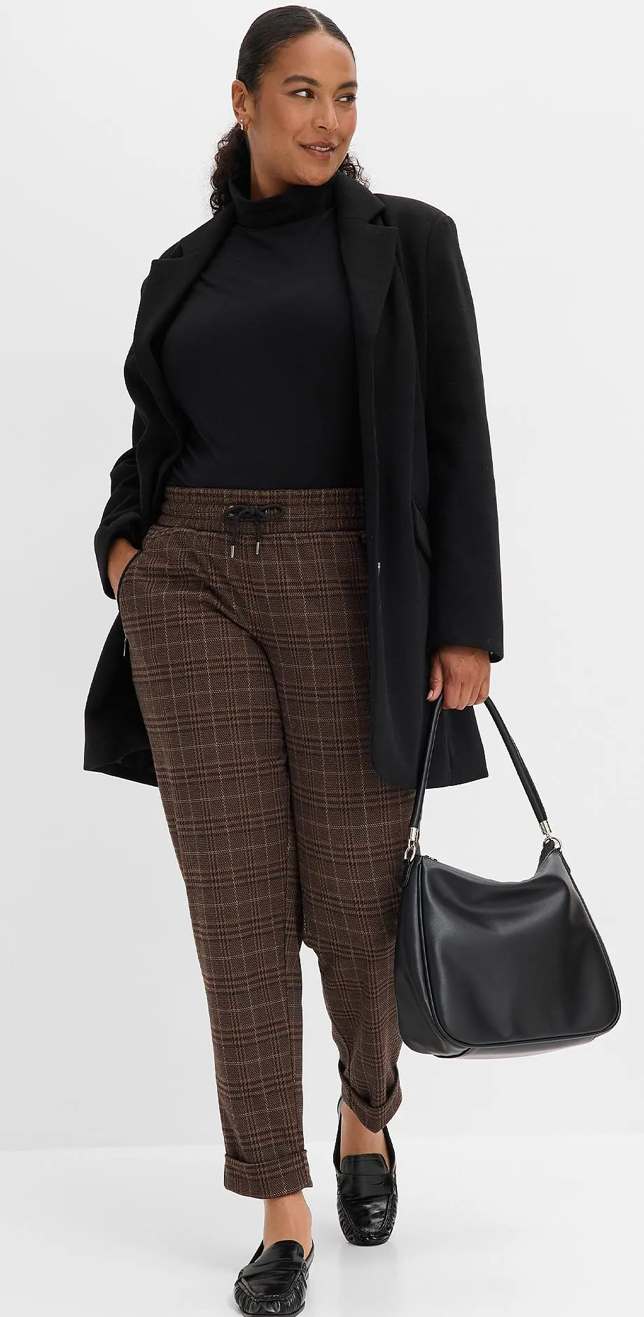 Sort, h&oslash;yhalset genser, lang blazer, rutete bukse, elegante sko og sort veske.
