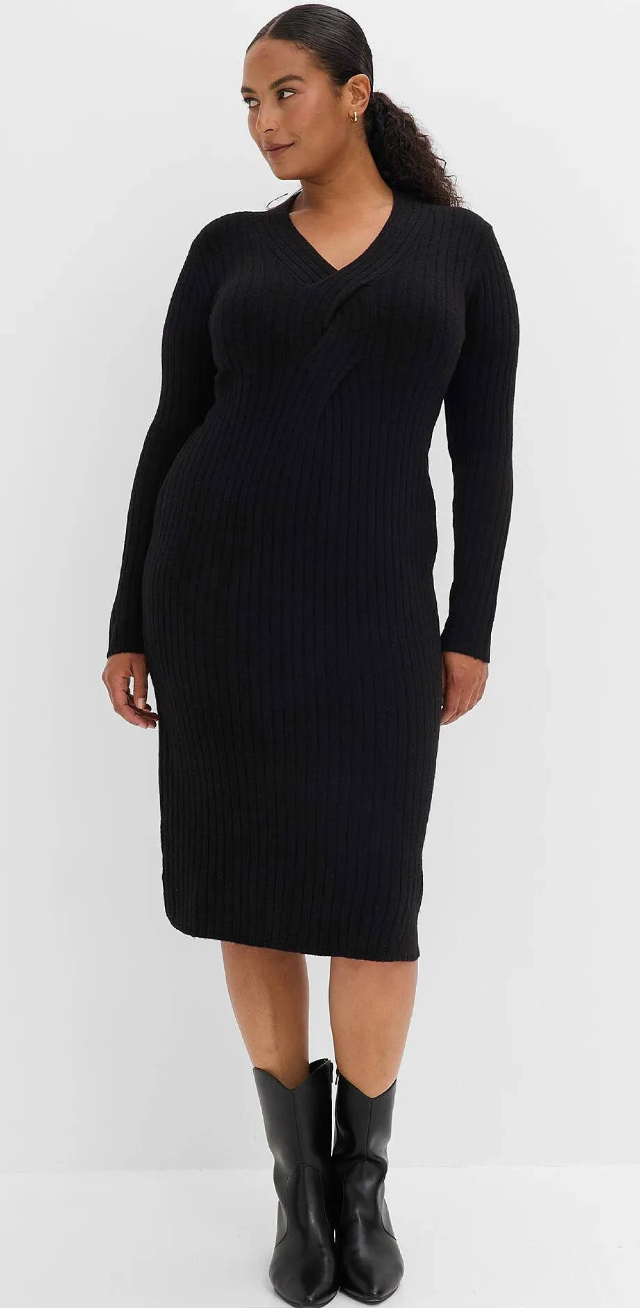 Hen kledd i elegant, sort og ribbestrikket kjole kombinert med sorte boots.