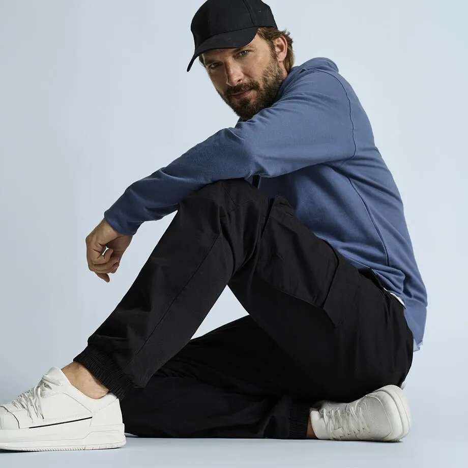 Kul stil: Sort caps, bl&aring; hoodie, behagelig, sort cargobukse og hvite sneakers.