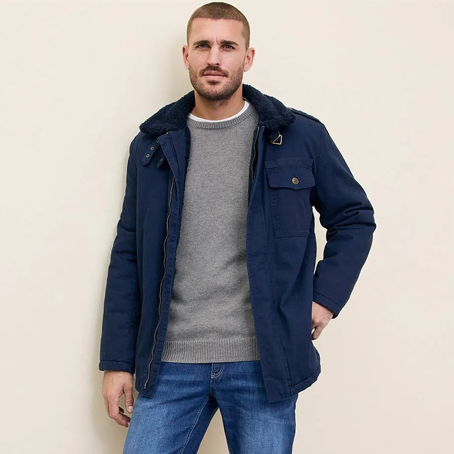 Bl&aring; jakke, gr&aring; genser og jeans.