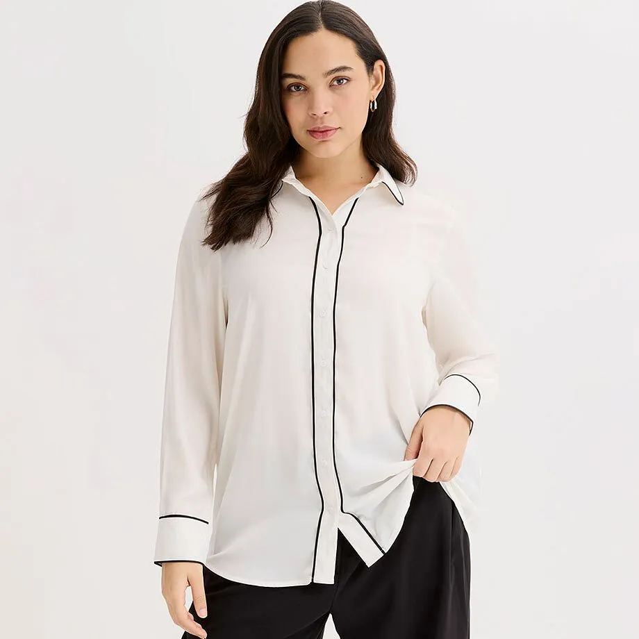 Hvit skjorte med sort passepoil, klassisk krage og lange ermer.