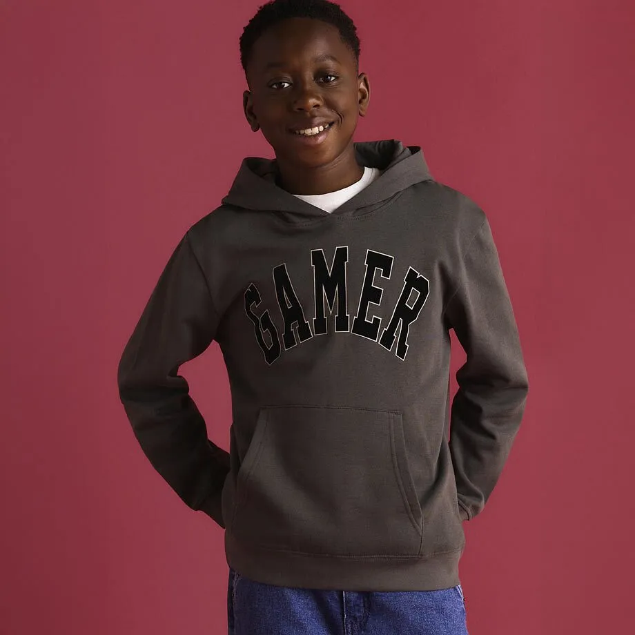 Gr&aring; og sort hoodie med "Gamer"-trykk og bl&aring; jeans.