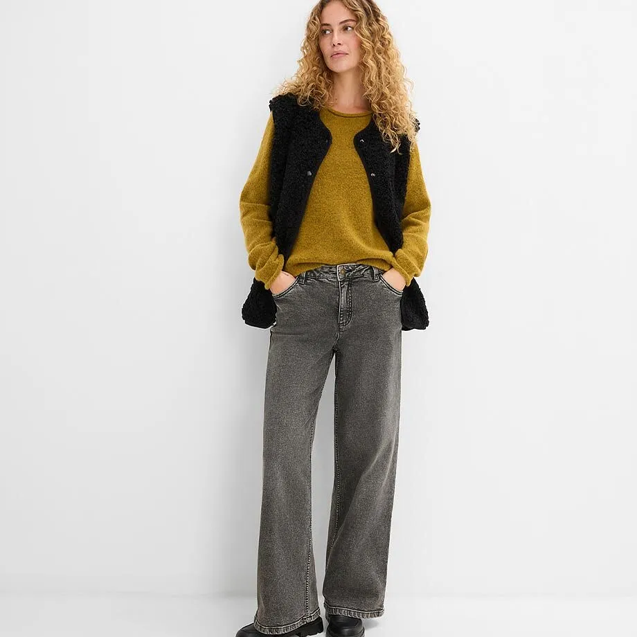 Sennepsgul genser, sort vest og gr&aring; jeans.
