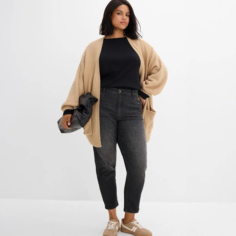 Beige cardigan over sort topp kombinert med gr&aring; jeans og beige sneakers.