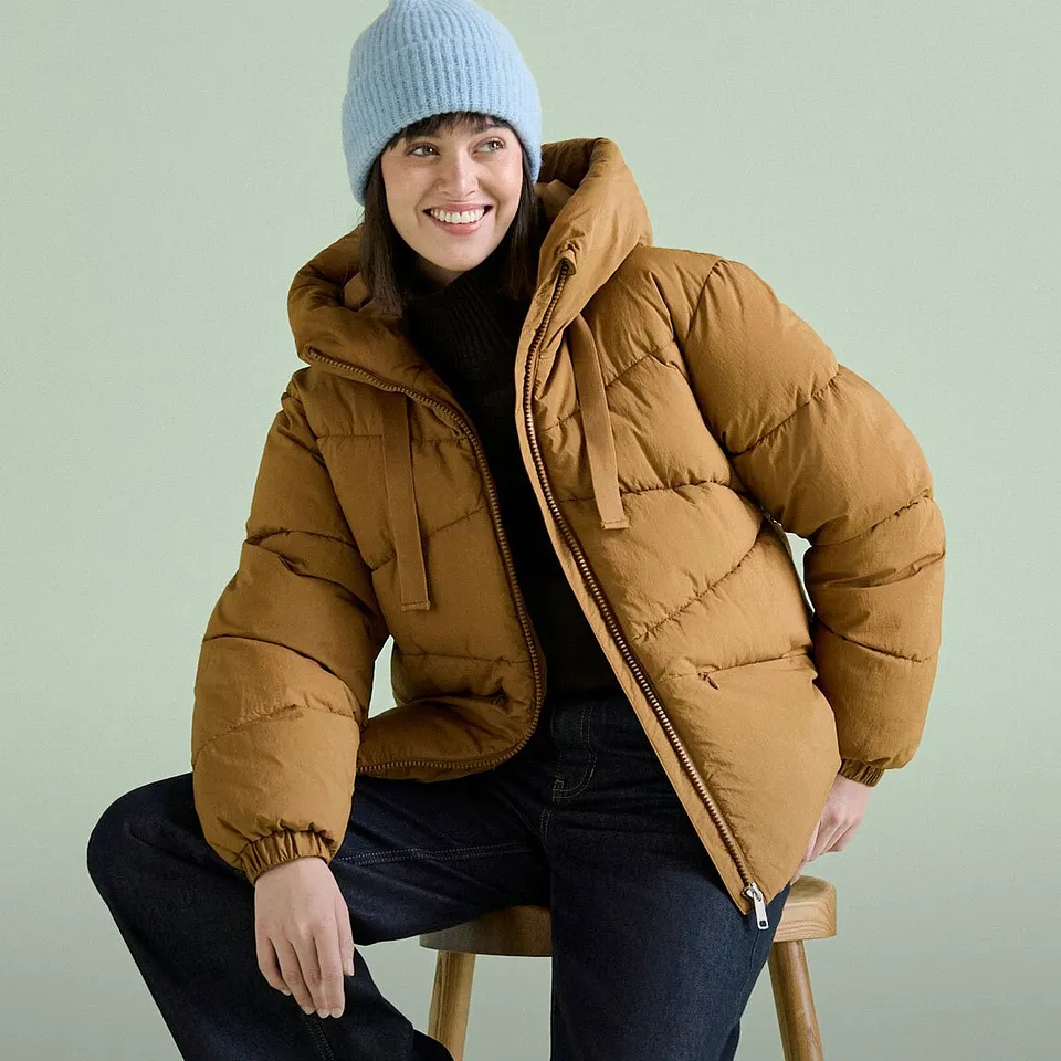 Bl&aring; lue, brun boblejakke og m&oslash;rke jeans.