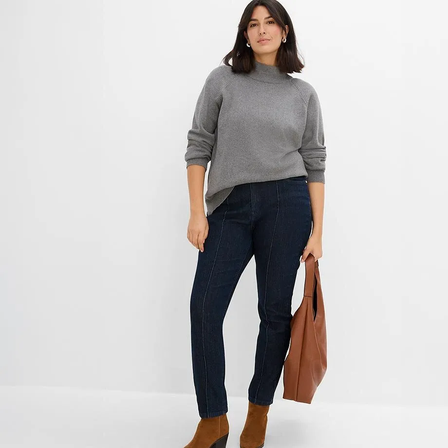 Gr&aring; genser, m&oslash;rke jeans, brune ankelst&oslash;vletter og veske.
