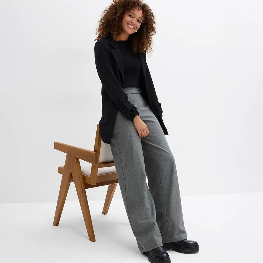 Sort topp, blazer, gr&aring;, vid bukse og chunky, sorte sko.