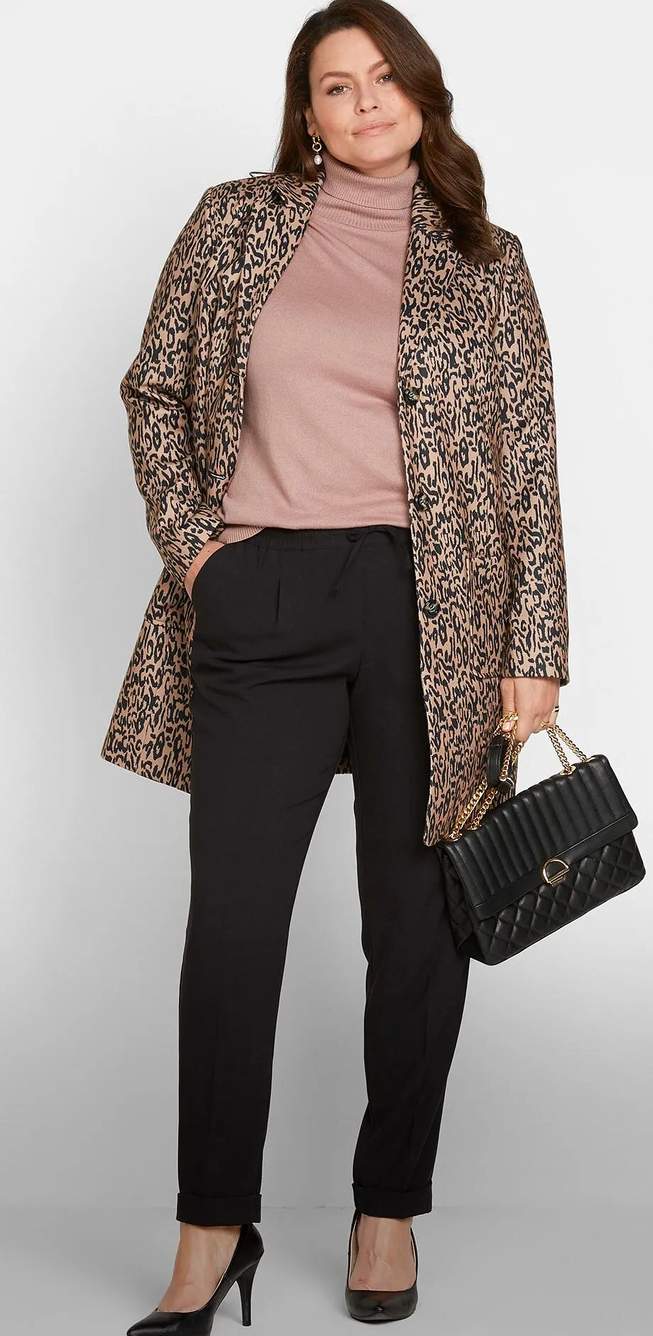 Stilfull, m&oslash;nstret k&aring;pe, rosa genser, sort bukse, pumps og h&aring;ndveske.