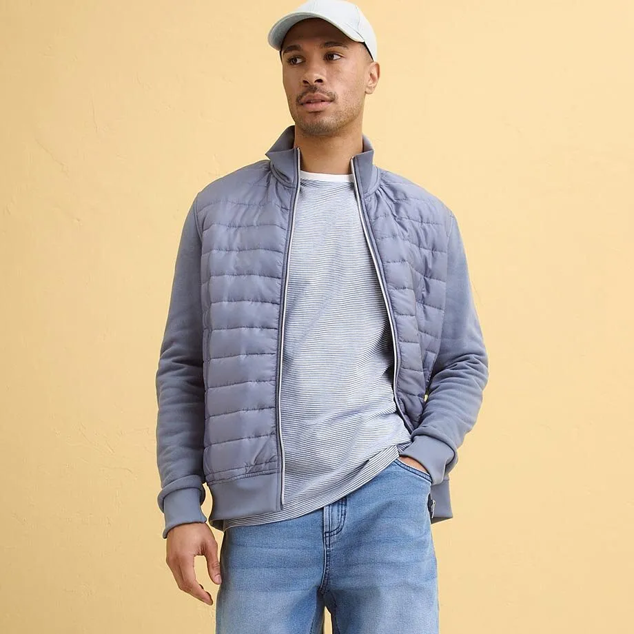 Gr&aring;bl&aring;, vattert jakke over lysegr&aring; shirt, bluejeans.