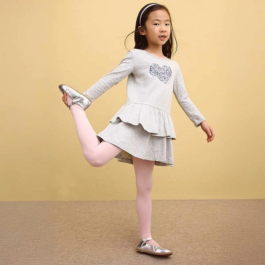 Jente i gr&aring; kjole med rysjer og rosa leggings.