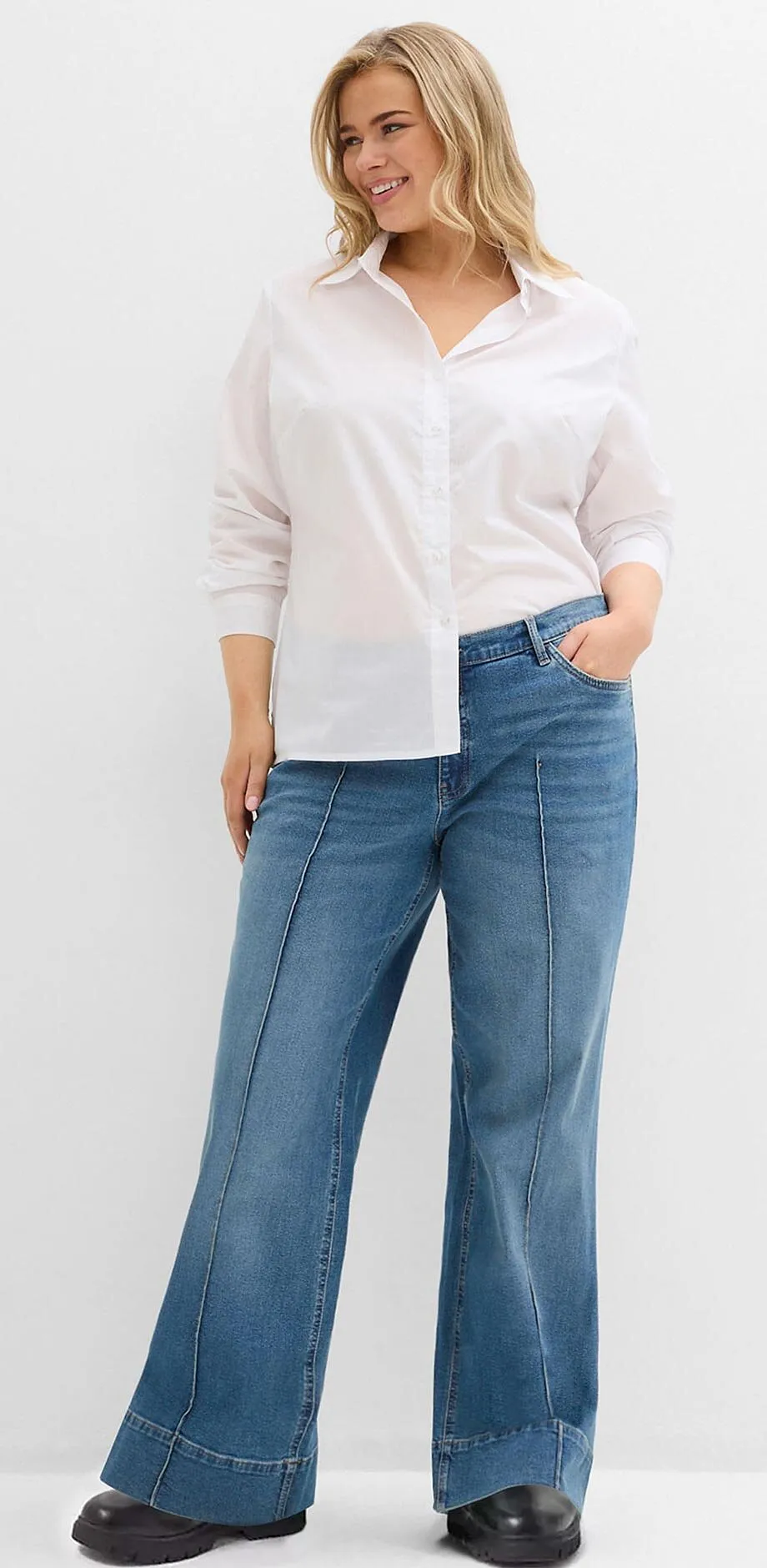 Hvit skjorte kombinert med vide jeans og sorte sko.